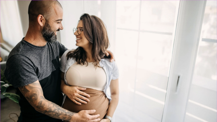 Expectant couple embracing with their hands on the mother's pregnant stomach